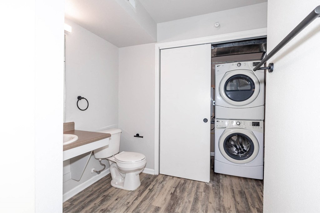 a bathroom with a toilet and a washing machine in it at Meadowlark Place Apartments, Grimes, Iowa