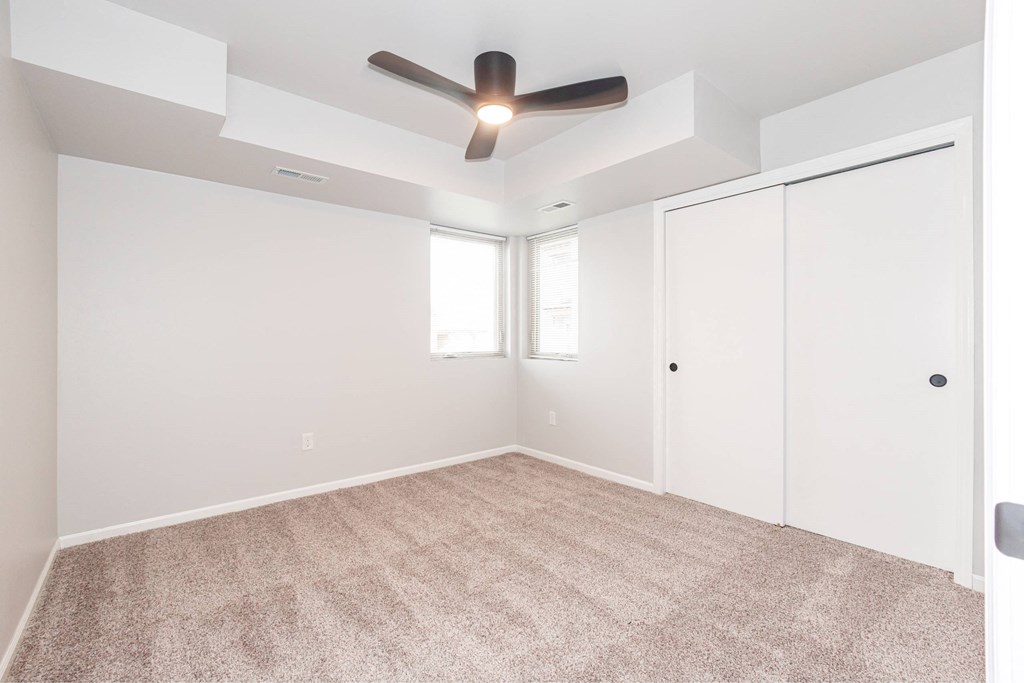 an empty room with a ceiling fan and a closet at Meadowlark Place Apartments, Grimes, IA
