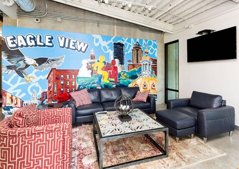 A living room with a large mural on the wall and a variety of furniture.