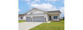 a white house with a driveway and a garage door at Two Rivers Home Rentals, West Des Moines, IA 50266
