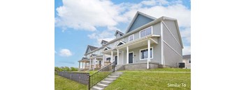 a large gray house with a porch and a green lawn at Two Rivers Home Rentals, West Des Moines