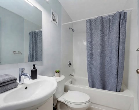 A white sink with a grey towel and a black soap dispenser on top of it.