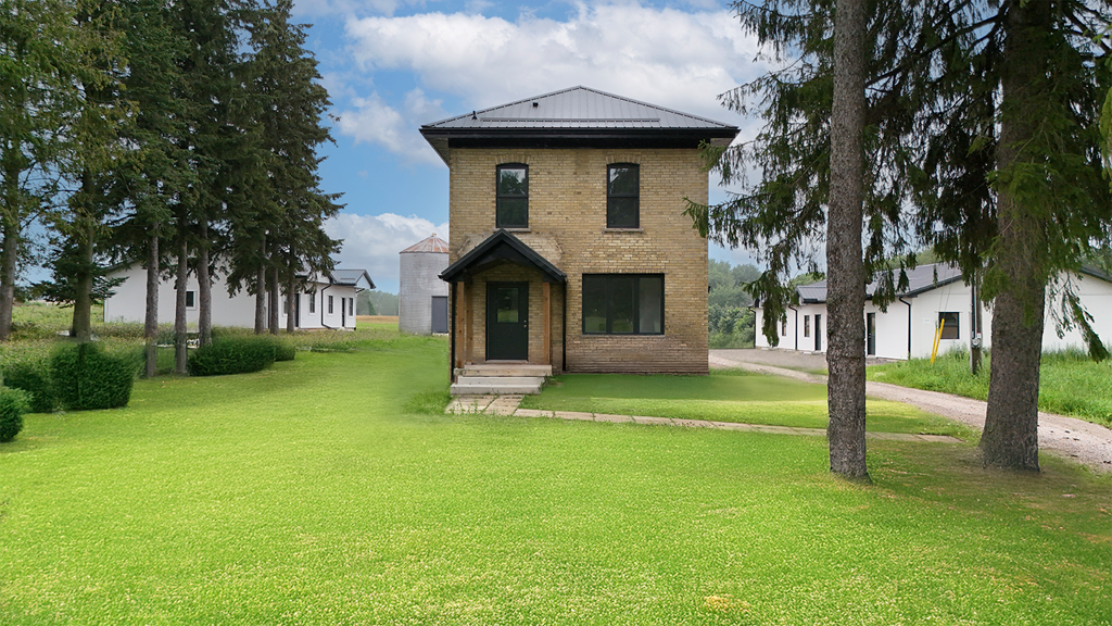 A small house with a black roof is surrounded by a green lawn.
