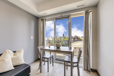A dining room with a table and chairs and a view of the city.