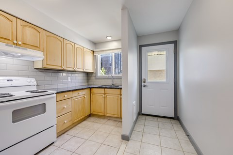 A kitchen with wooden cabinets and a white stove top oven.