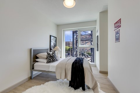 A bedroom with a bed and a window overlooking a city.