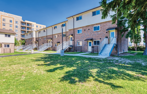 A sunny day at a grassy courtyard with apartment buildings in the background.