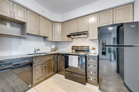 A kitchen with wooden cabinets and a black fridge.