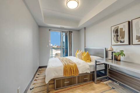 A bedroom with a bed, nightstand, and window.