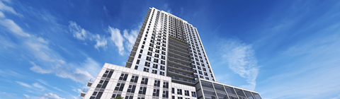 A tall building with many windows stands under a blue sky.