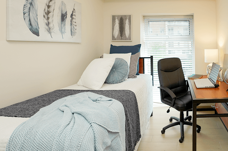 a bedroom with a bed and a desk with a laptop