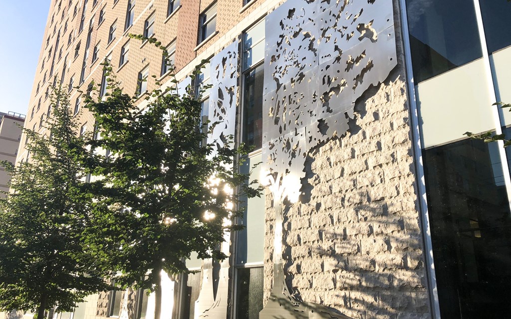 the side of a brick building with a window and a tree