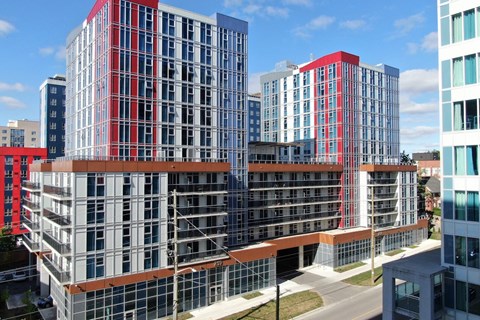 A modern building with red and blue accents stands tall against a clear sky.
