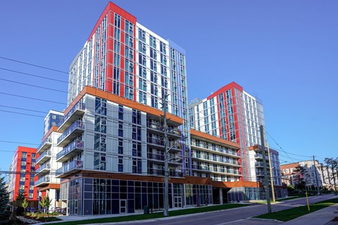 A modern building with red and blue accents stands tall against a clear blue sky.