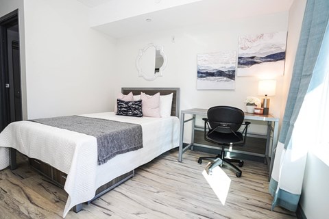 A bedroom with a bed, desk, and chair.