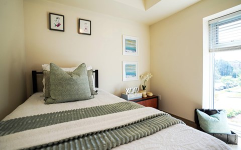 A bed with a striped comforter and a pillow with the word XOXO on it.
