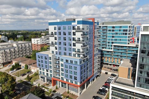 A modern multi-story building with a parking lot in front.