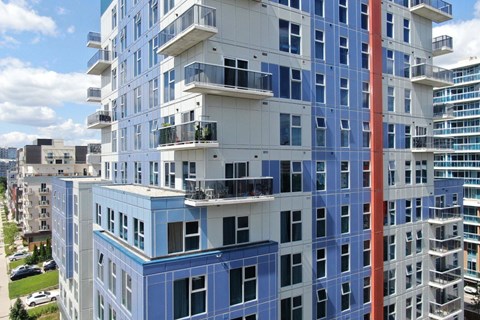 A tall building with balconies and a red column in the middle.