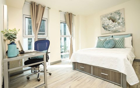 A bedroom with a bed, desk, and chair.