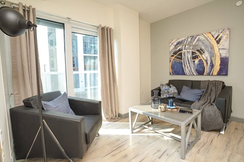 A living room with a grey couch, a coffee table, and a painting on the wall.