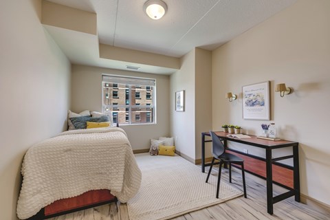 A bedroom with a bed, desk, and chair.