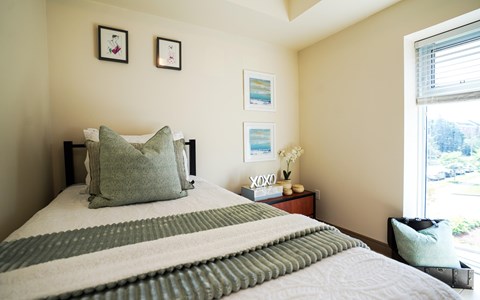 A bed with a green and white striped blanket and a green pillow is in the foreground of the image.