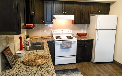 A kitchen with a white stove and black cabinets.