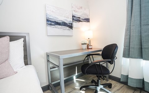 a desk with a chair in a room with a bed