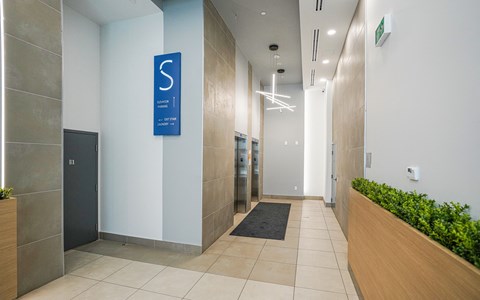 a hallway of elevators in a building with a blue sign on the wall