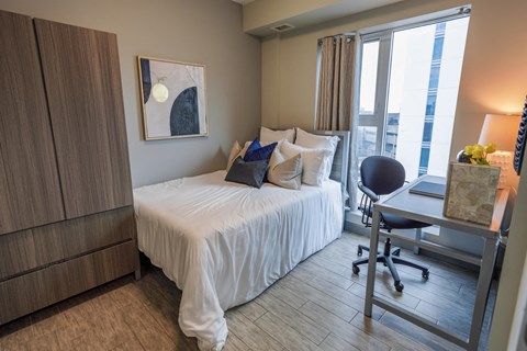 a bedroom with a bed and a desk and a window