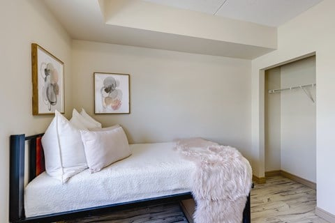 A bedroom with a bed, pillows, and pictures on the wall.