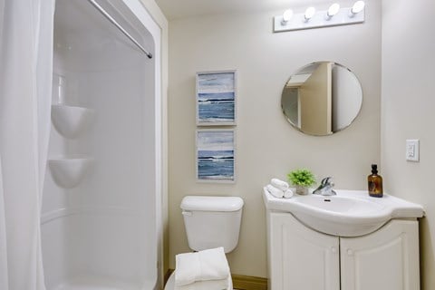 A white bathroom with a toilet, sink, and mirror.