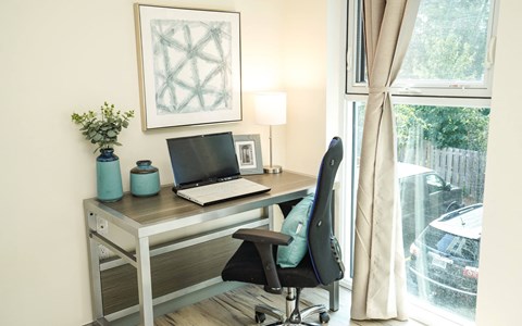 a home office with a laptop on a desk and a window