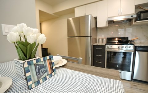 a kitchen with stainless steel appliances and a table with a vase of flowers