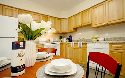 A kitchen with wooden cabinets and a table set for a meal.