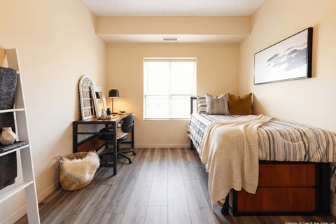 A bedroom with a bed, desk, chair, and a cat.