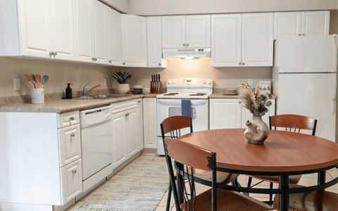 A kitchen with white cabinets and a wooden table.