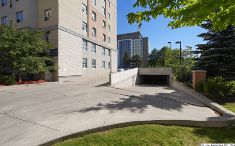 A parking lot in front of a building with a tall tree on the right.