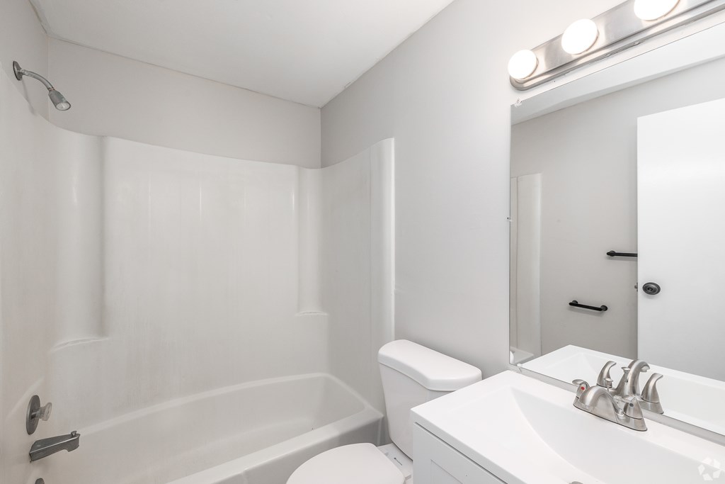 A white bathroom with a toilet, sink, and bathtub.