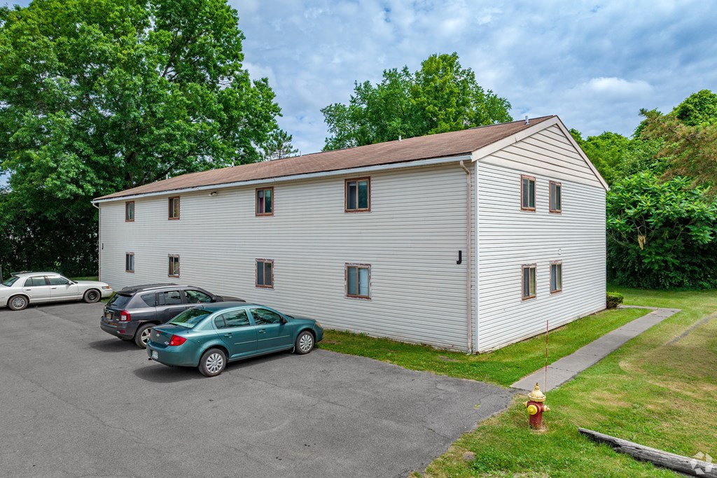 A white house with a green car parked in front.