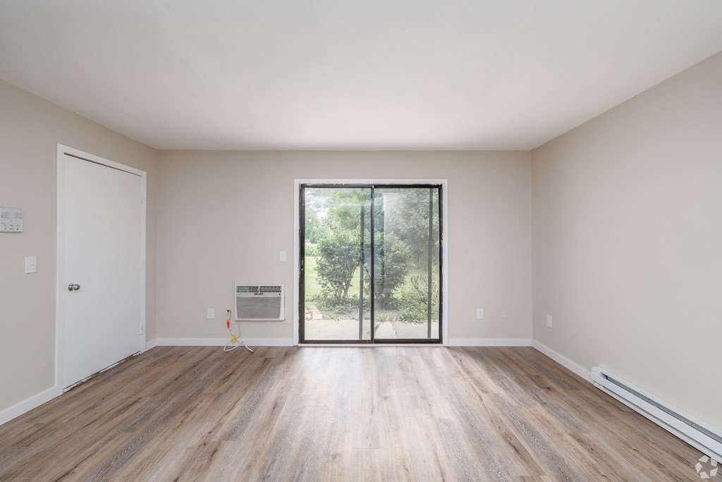 A room with wooden floors and a sliding glass door leading to a backyard.