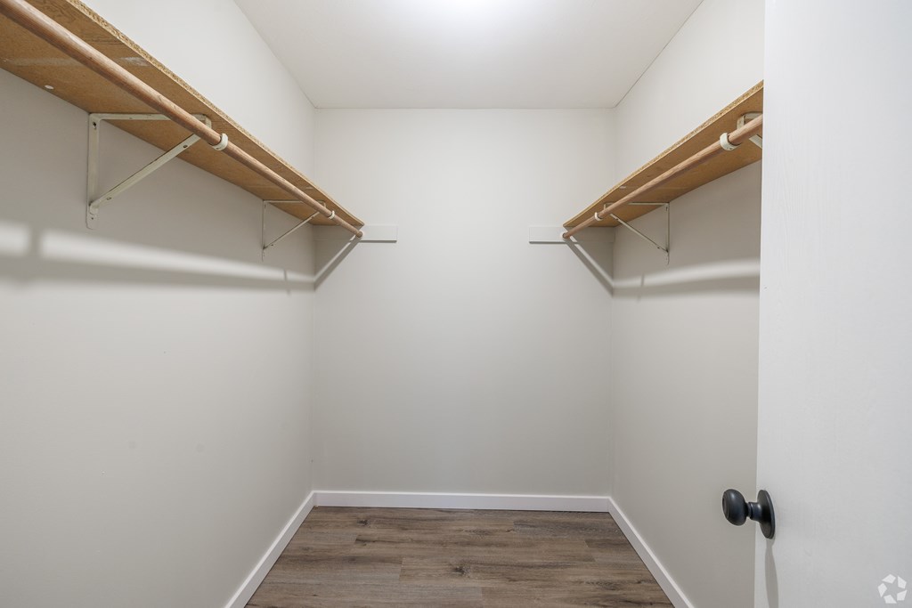 A white room with a wooden floor and two shelves.