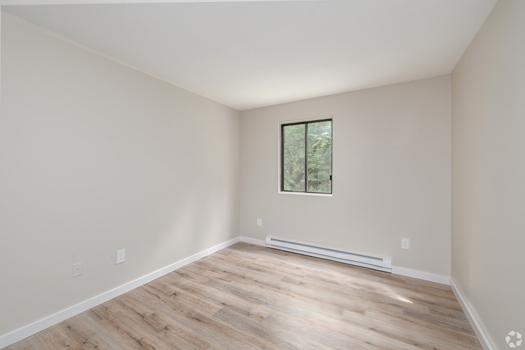 A room with a window and a radiator on the floor.
