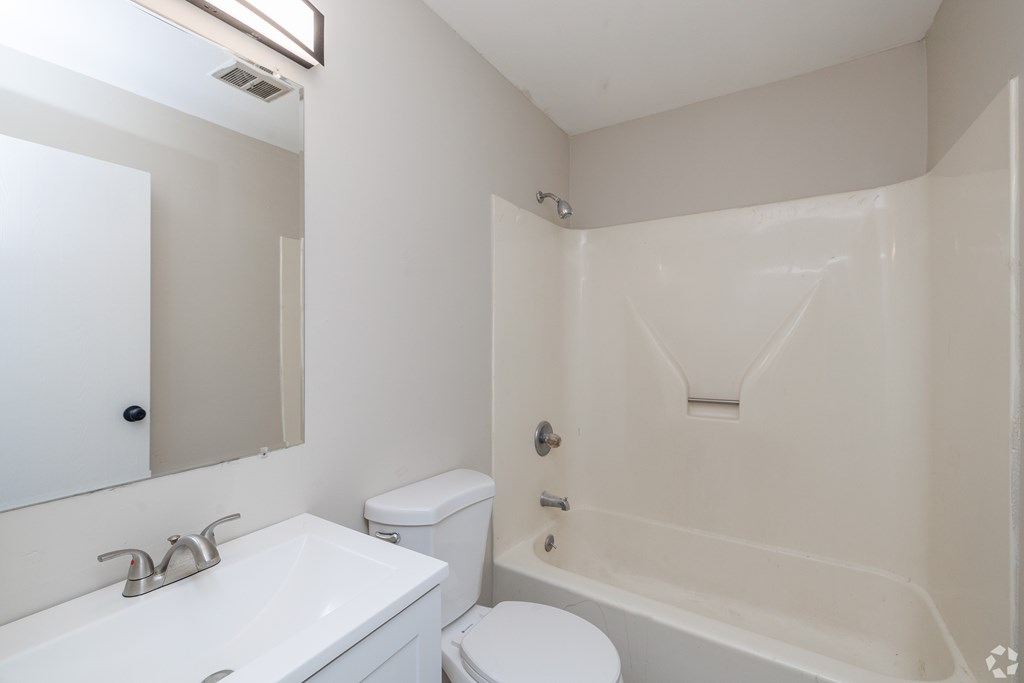A white bathroom with a toilet, sink, and bathtub.