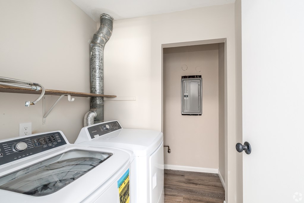 A washing machine is sitting in a laundry room next to a pipe.