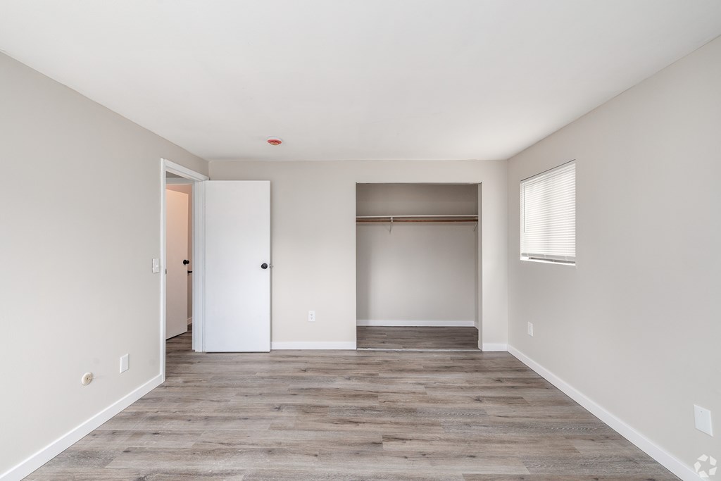A room with a white door and a window with blinds.