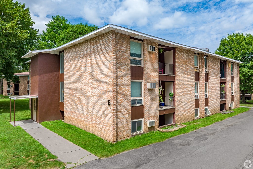 A brick apartment building with a green lawn in front.
