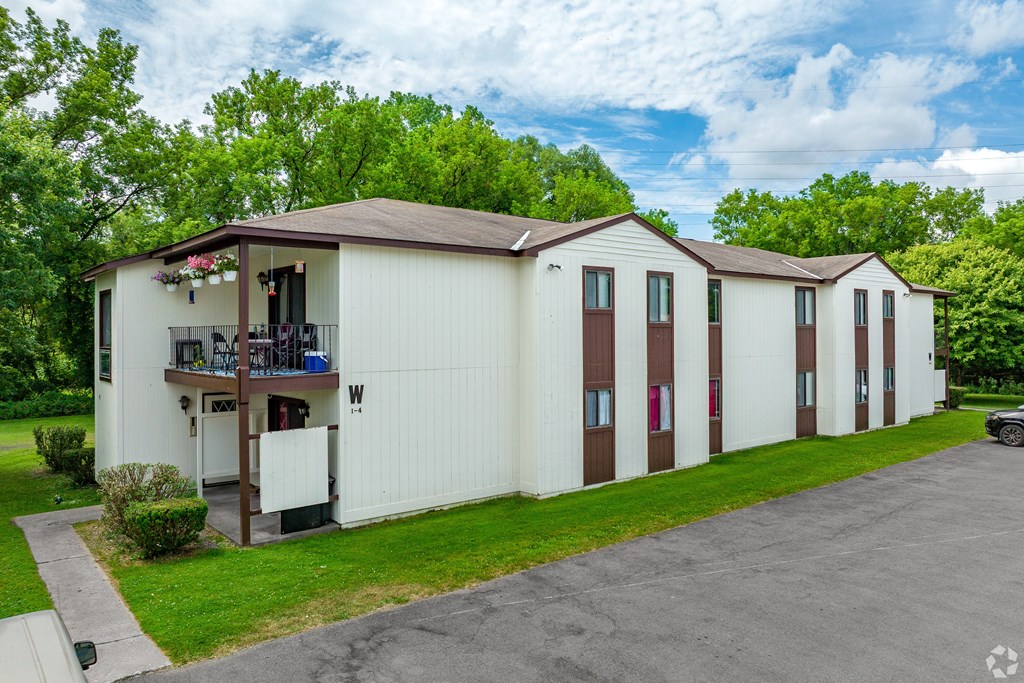 A white mobile home with a brown roof and a balcony on the front.