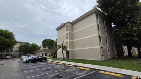 A parking lot in front of a beige building.