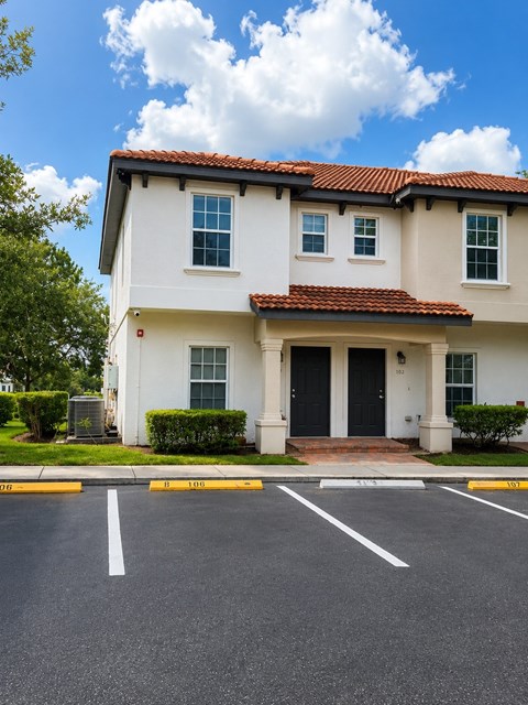A white house with a red tile roof and a black front door.